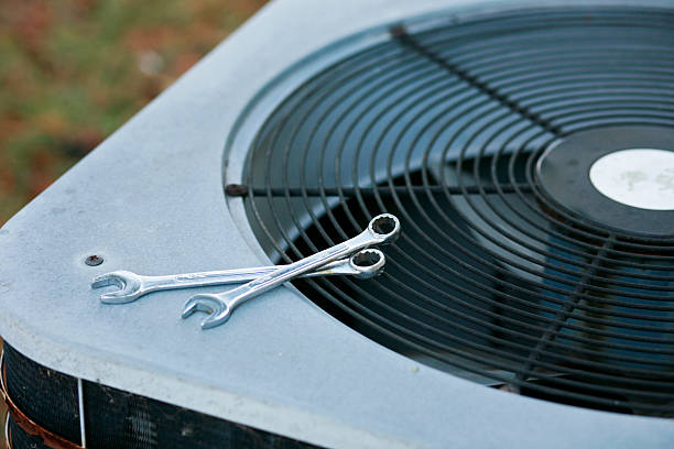 HVAC technician's tools and condenser unit during a maintenance tune-up
