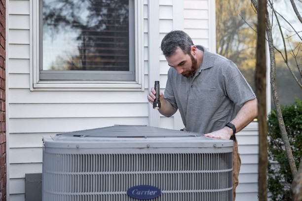 HVAC technician inspecting an outdoor air conditioning condenser unit